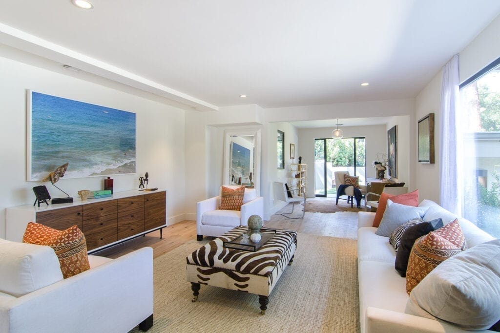 A living room with white furniture and a zebra print couch.