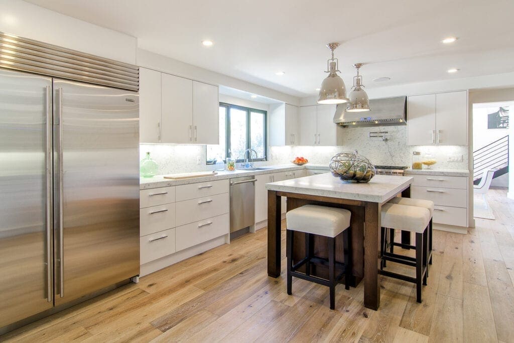 A kitchen with white cabinets and wooden floors.