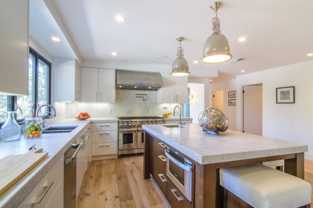A kitchen with white cabinets and wooden floors.
