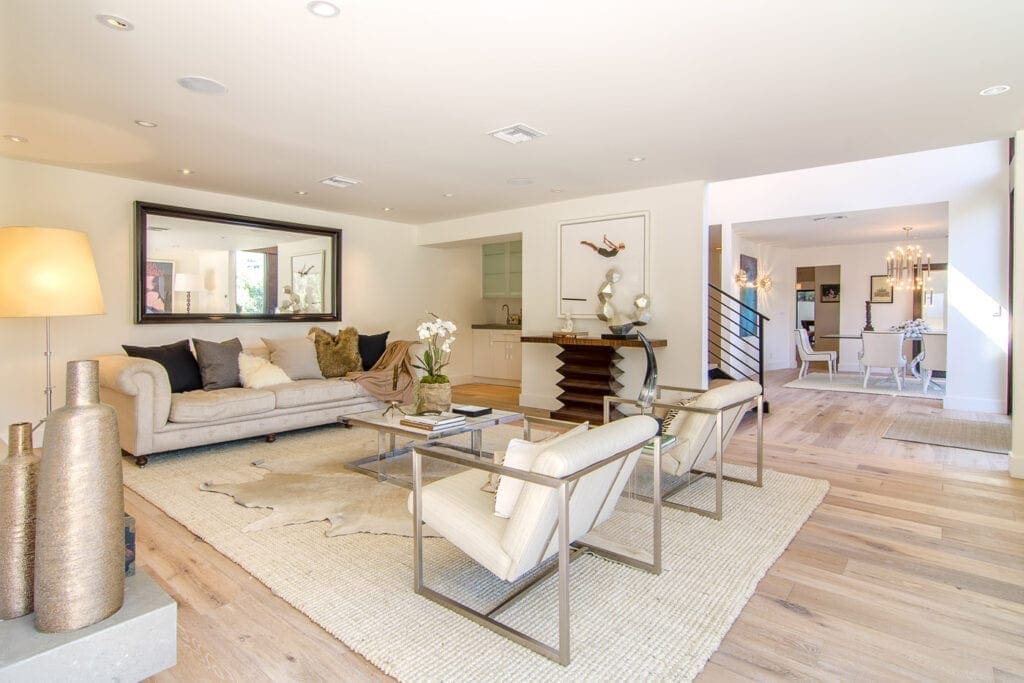 A living room with white furniture and wood floors.