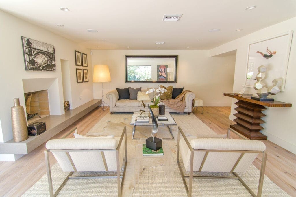 A living room with white furniture and a large mirror.