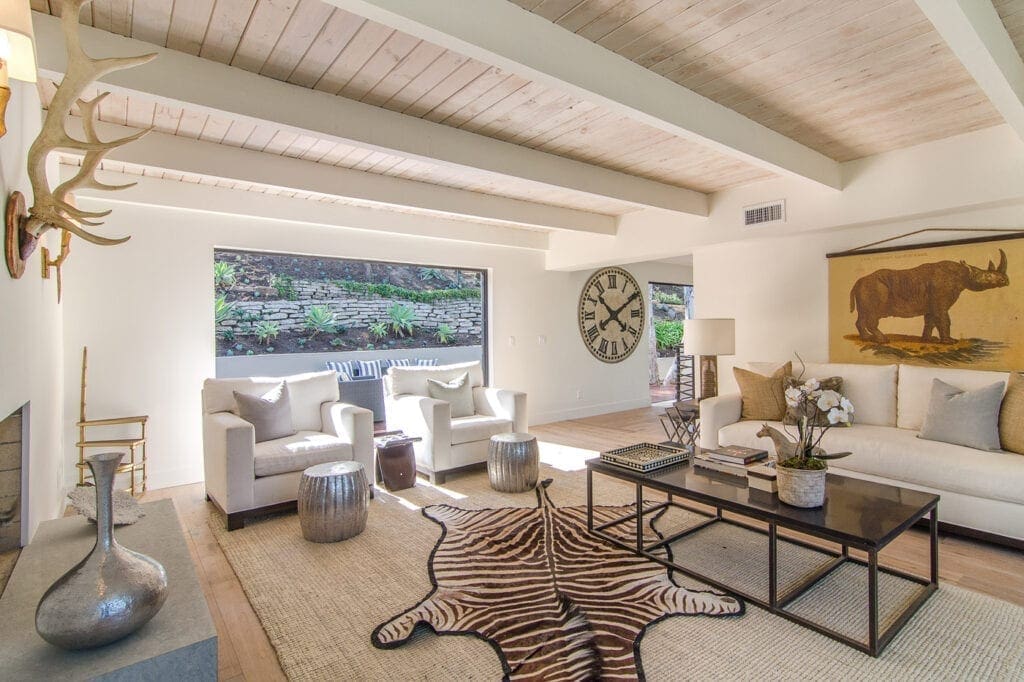A living room with white furniture and wood ceiling.