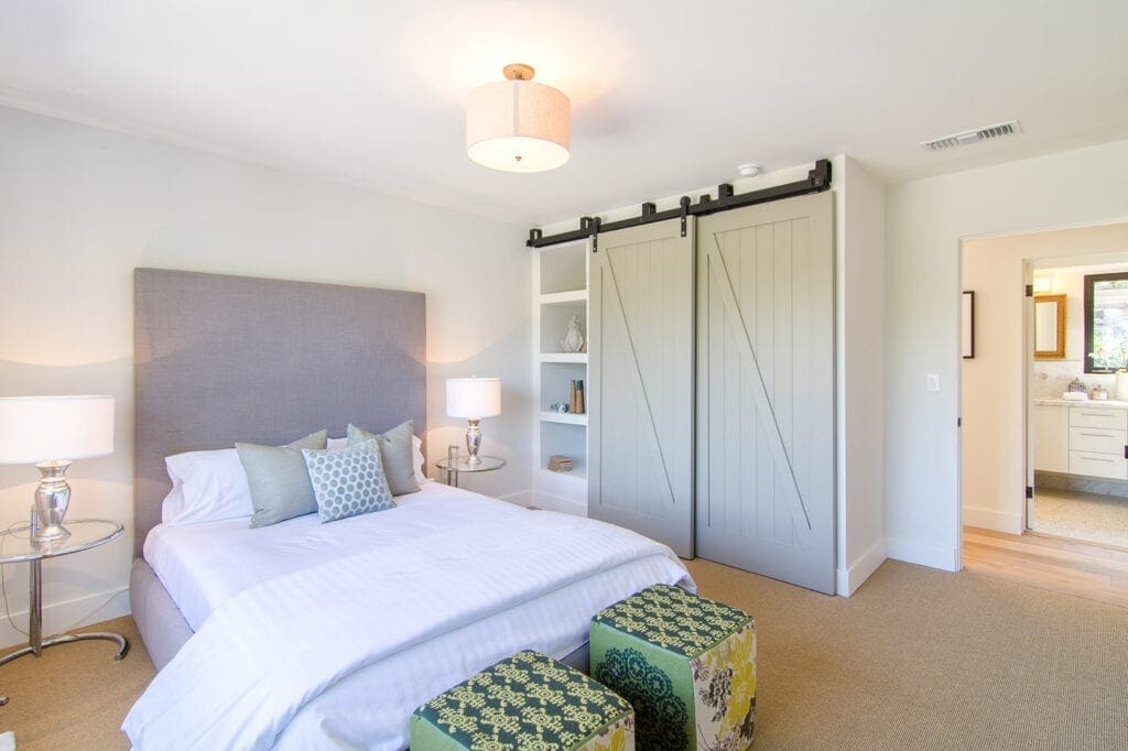 A bedroom with a bed, nightstand and sliding door closet.
