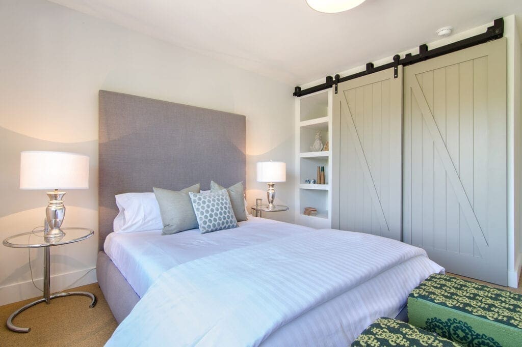 A bedroom with a bed, nightstand and sliding door.