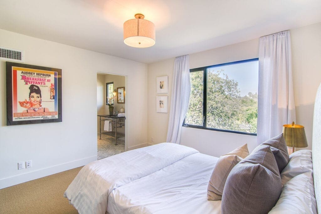A bedroom with two beds and a large window.