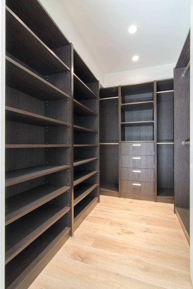A large walk in closet with shelves and drawers.