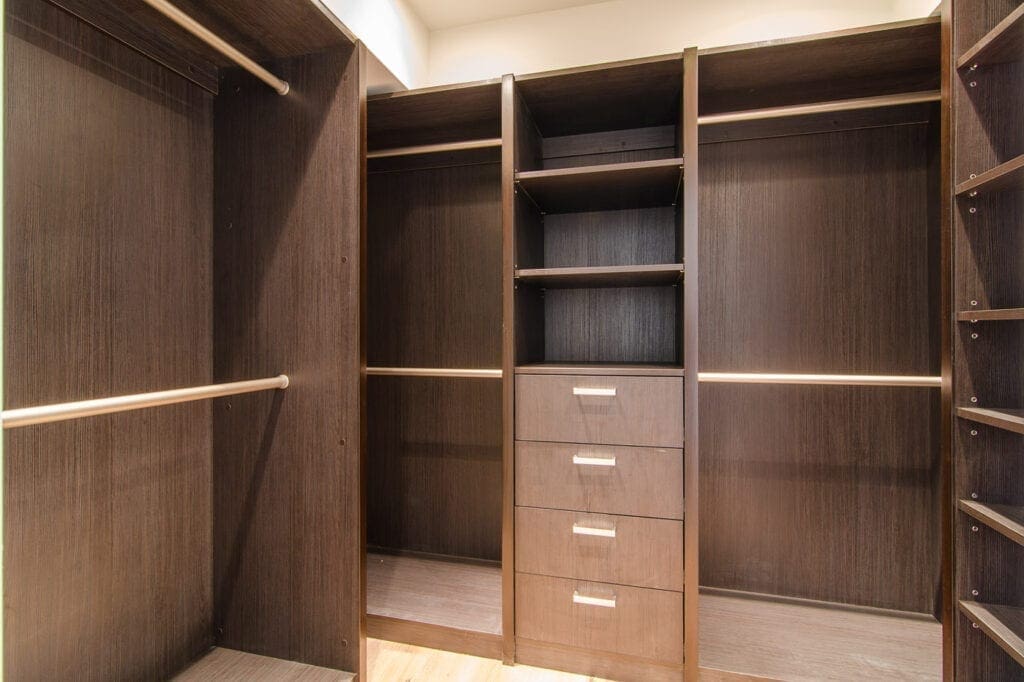 A large walk in closet with wooden shelves and drawers.