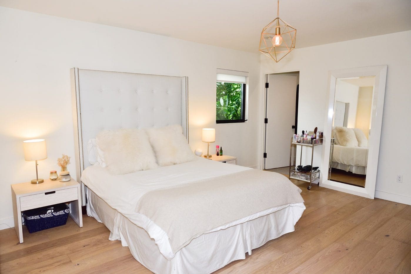 A bedroom with white walls and wooden floors.