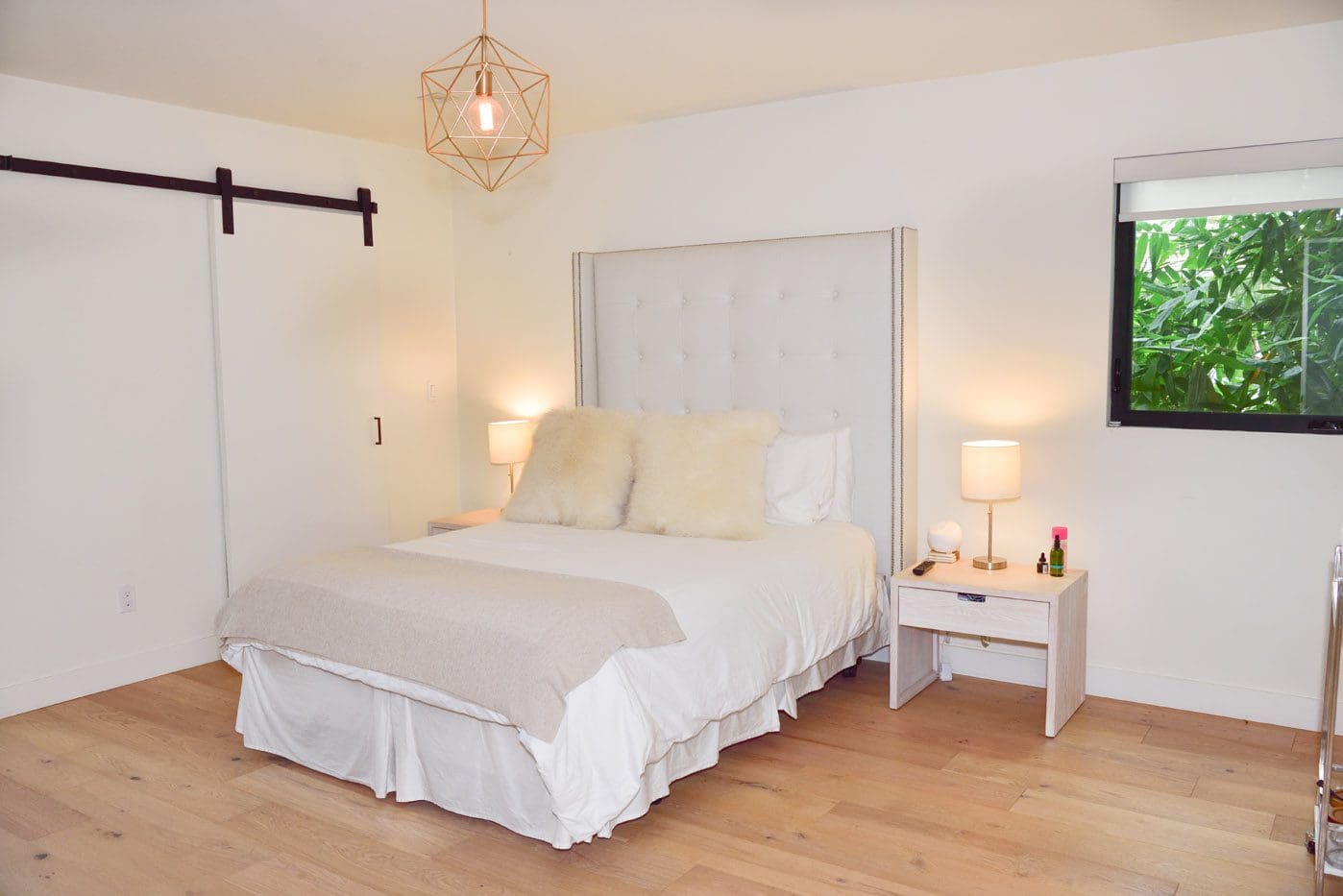 A bed room with a white bedspread and pillows