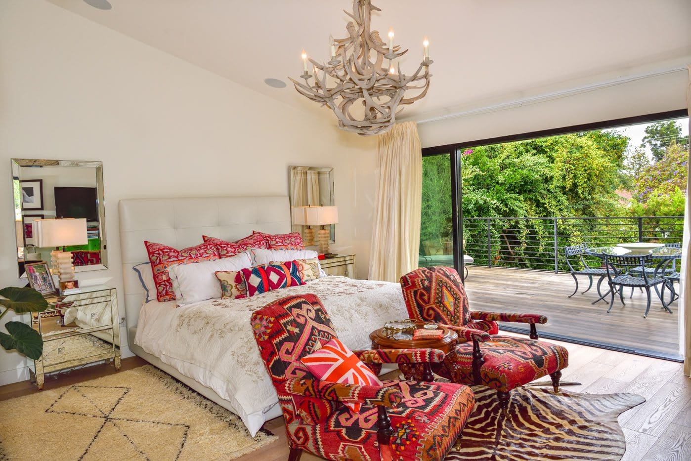 A bedroom with a bed, chair and chandelier.