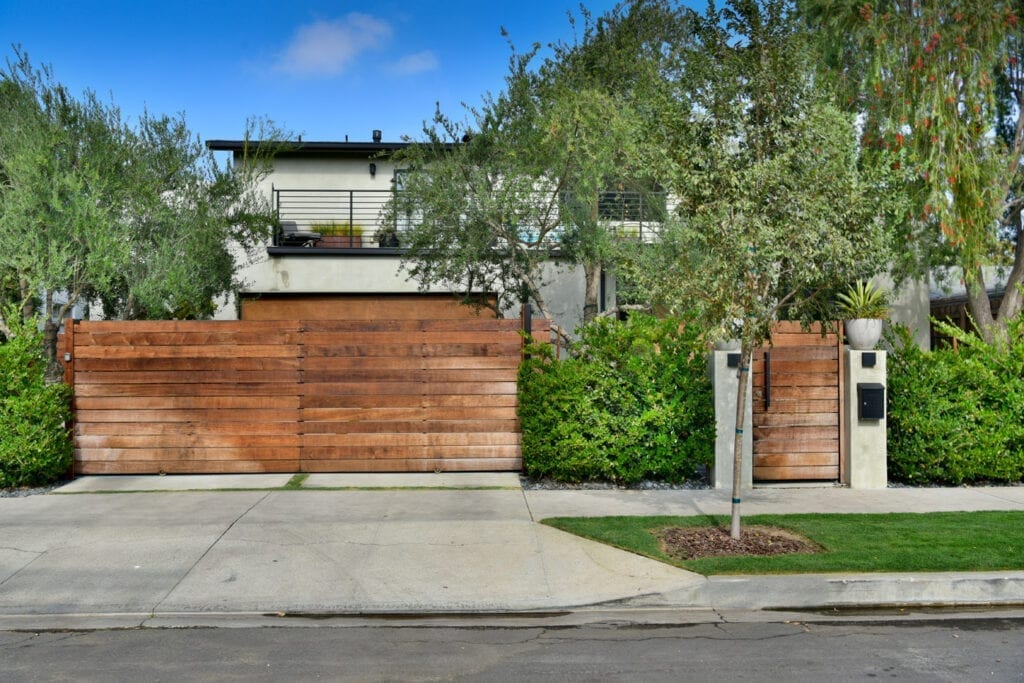 A driveway with trees and a wooden fence.