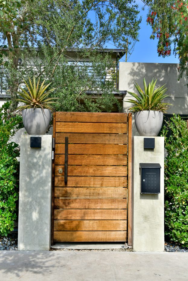 A wooden gate with plants on the side of it.