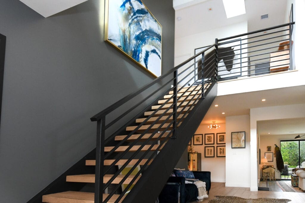 A staircase with metal railing and black handrail.