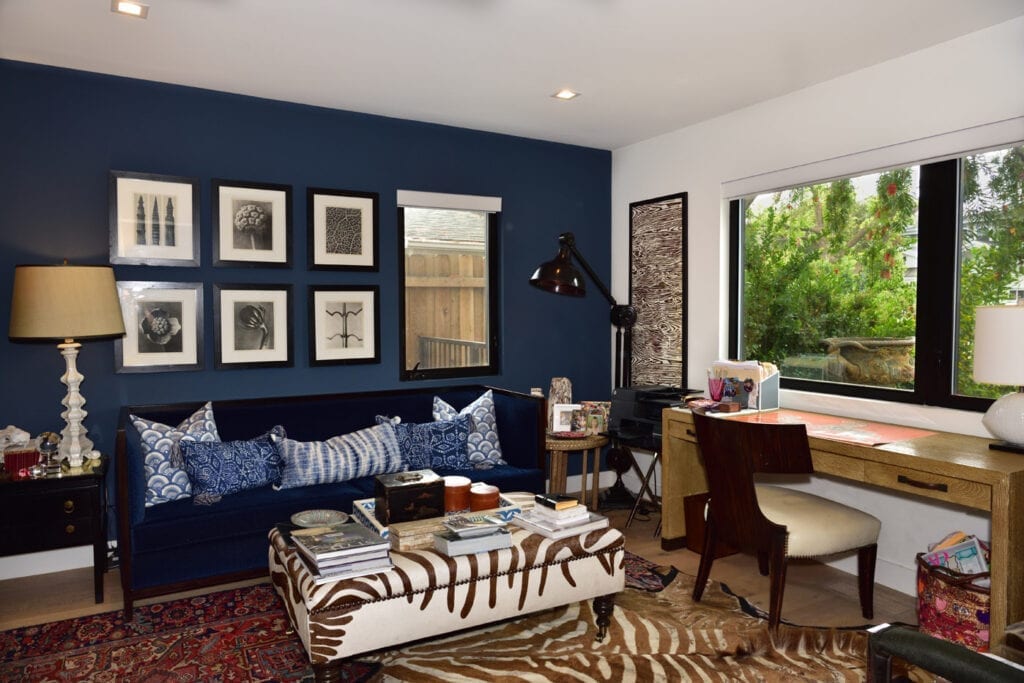 A living room with blue walls and zebra print furniture.