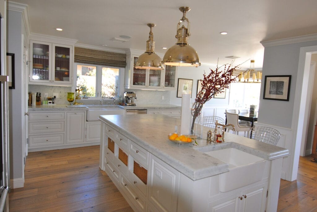 A kitchen with white cabinets and gold fixtures.