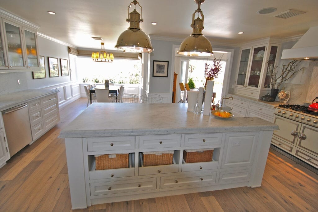 A kitchen with white cabinets and gold lights