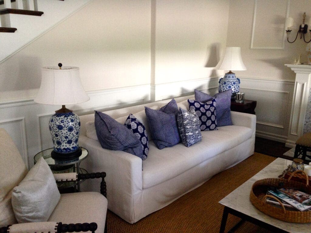 A living room with white furniture and blue pillows.