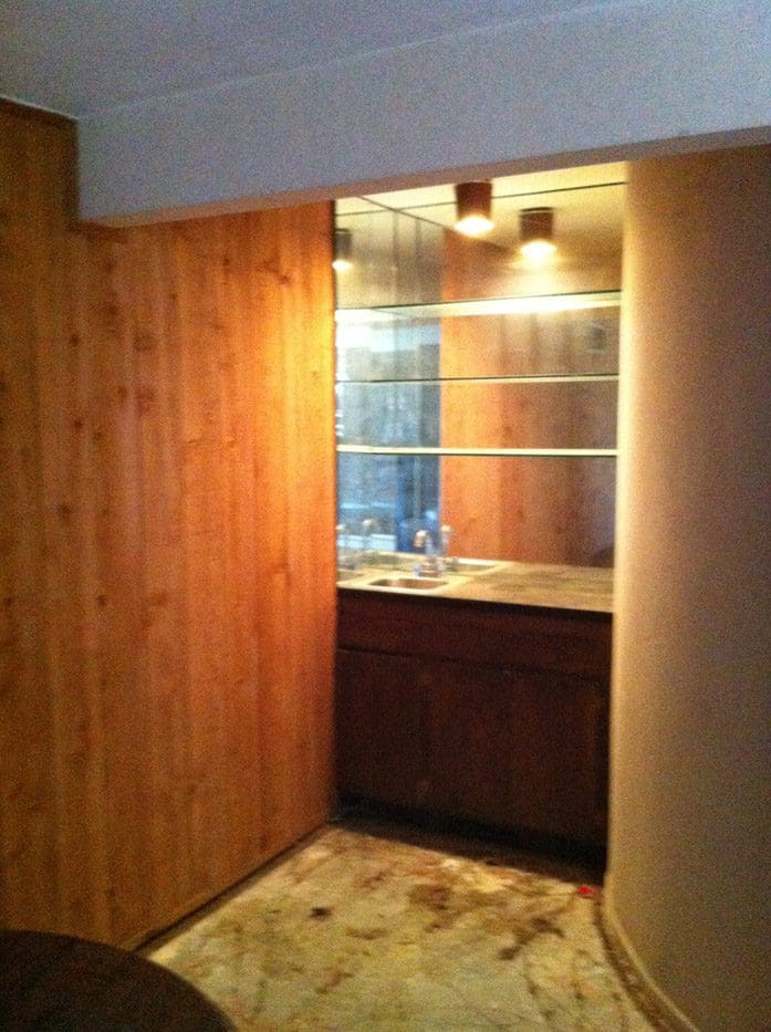 A bathroom with wood paneling and lights on the wall.