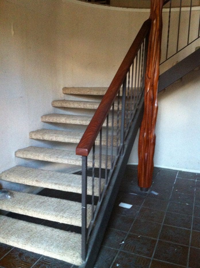 A staircase with wooden handrails and carpet on the bottom.