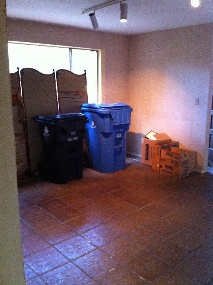 A room with boxes and trash cans in it.
