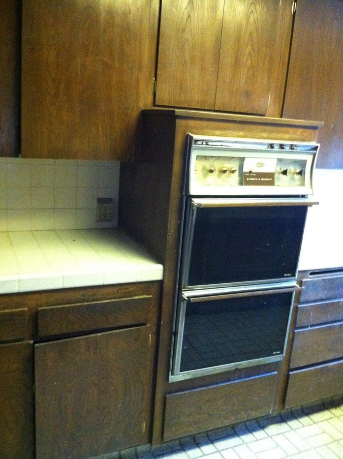 A kitchen with two ovens and wooden cabinets.