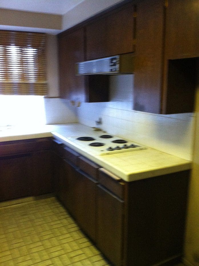 A kitchen with brown cabinets and white counters.