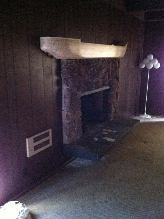 A fireplace in the corner of a room with purple walls.