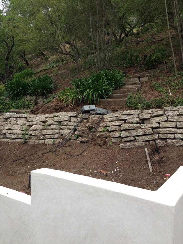 A stone wall in the middle of a garden.