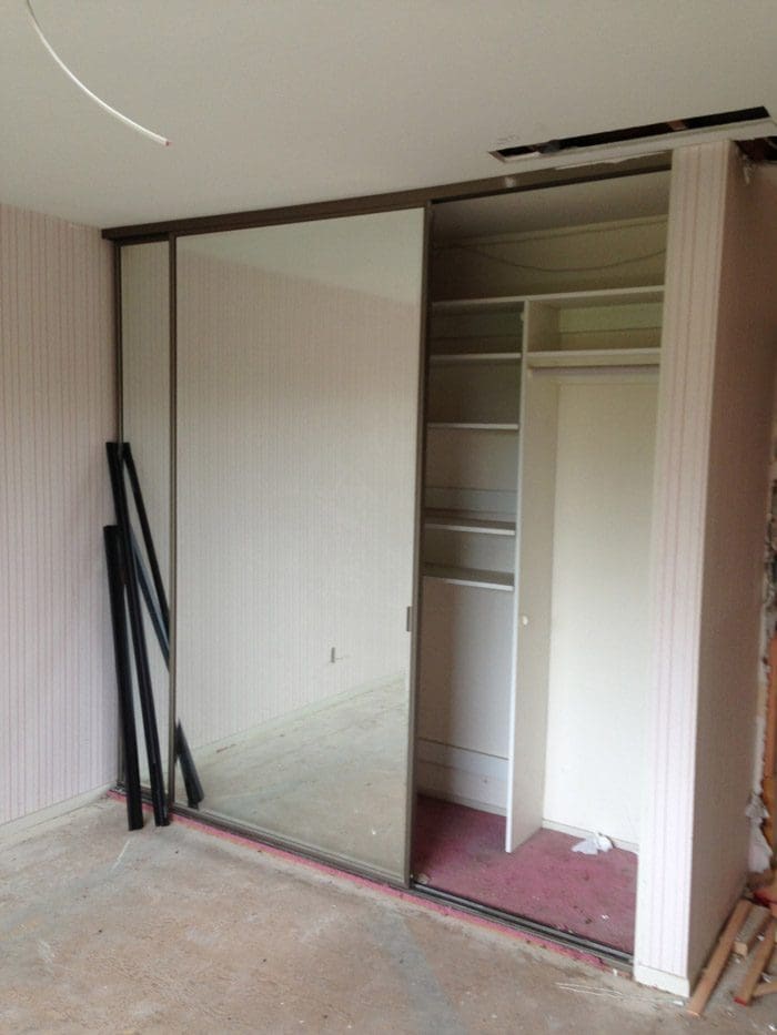 A room with a mirror and some shelves