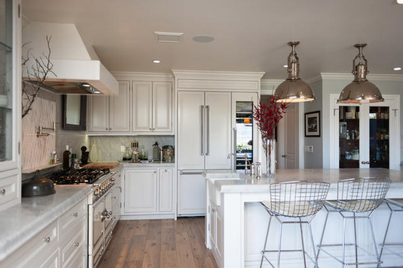 A kitchen with white cabinets and wooden floors.