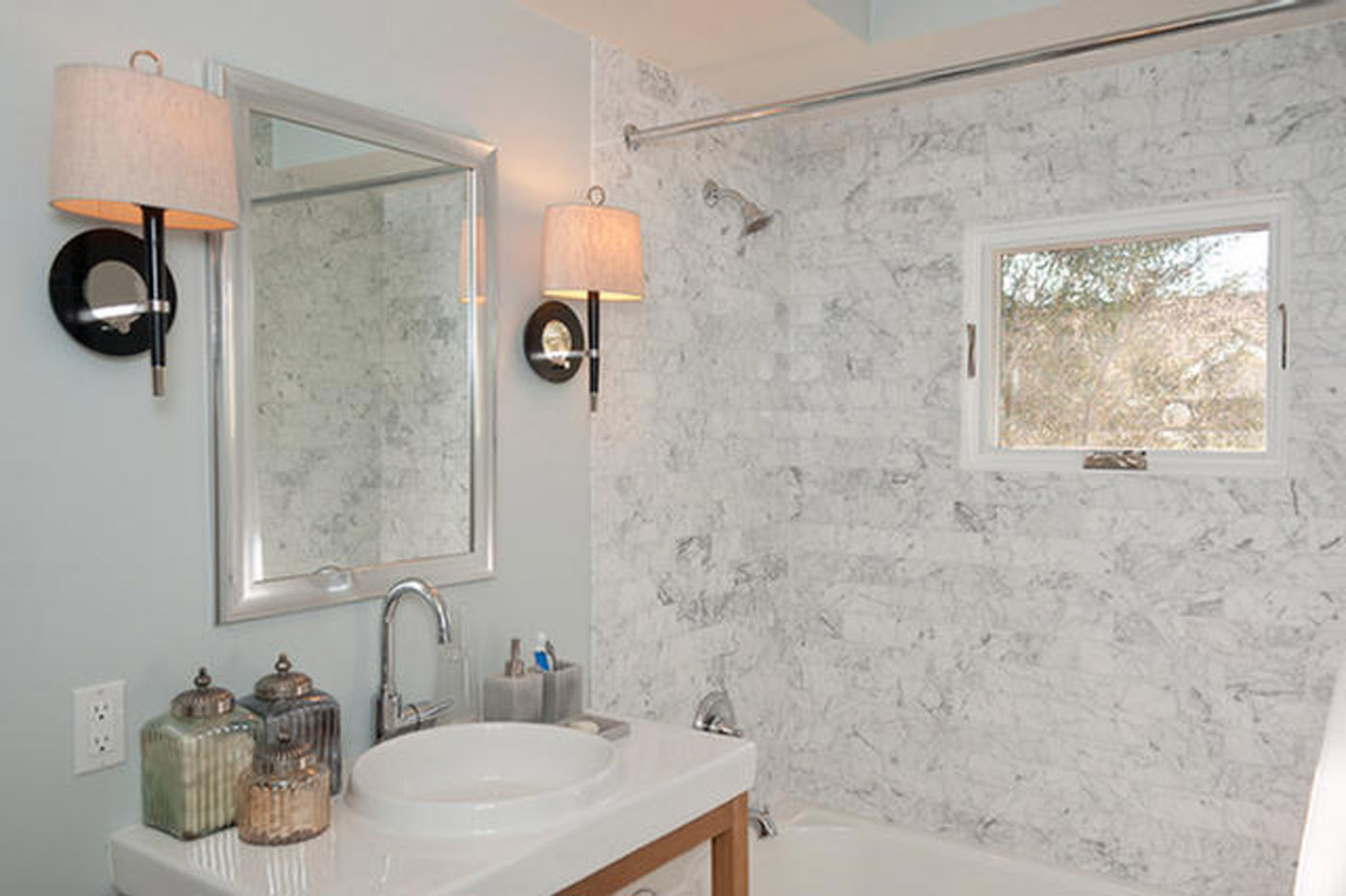 A bathroom with marble walls and white fixtures.