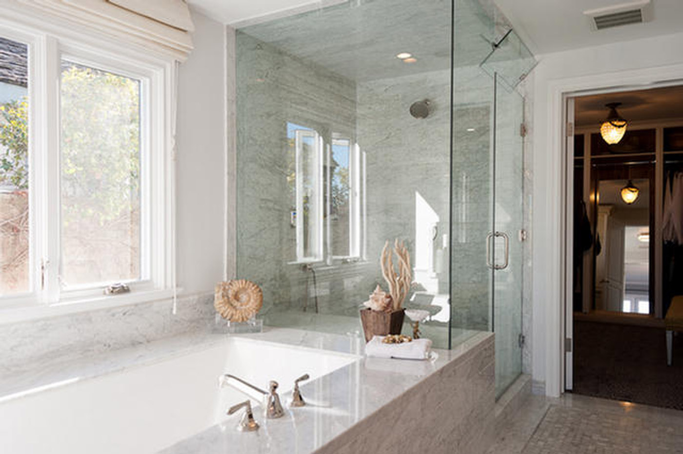 A bathroom with a large glass shower and marble counter.