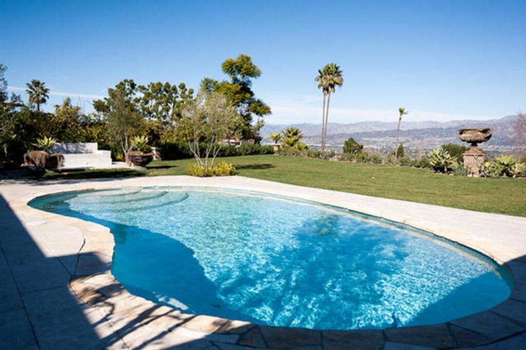 A pool with an outdoor area in the background.