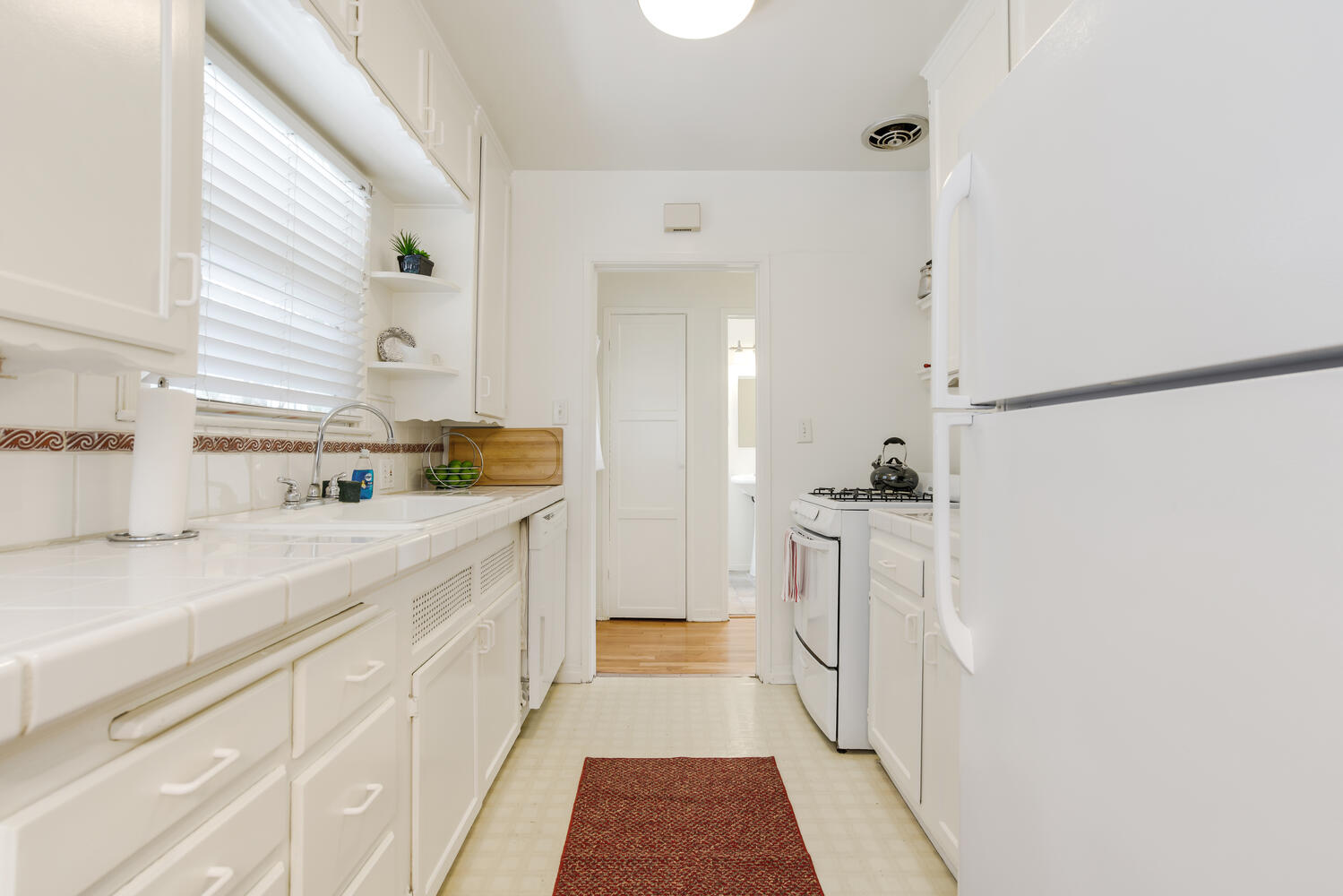 A kitchen with white cabinets and appliances in it.