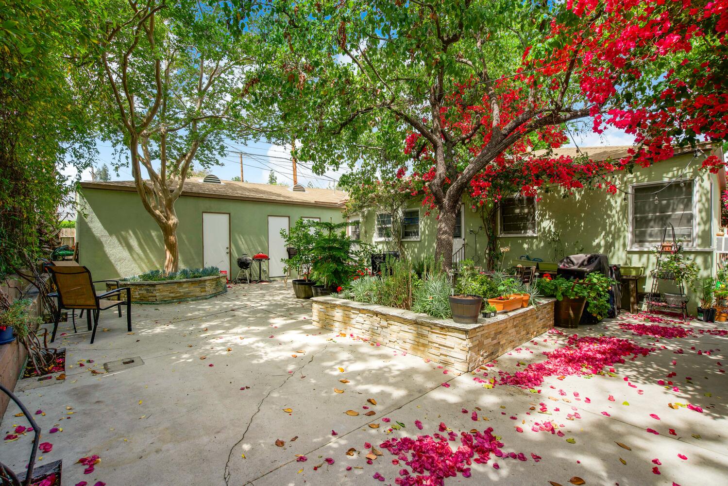 A patio with flowers and trees in the background.