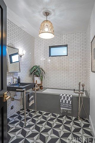 A bathroom with a tub, sink and mirror.