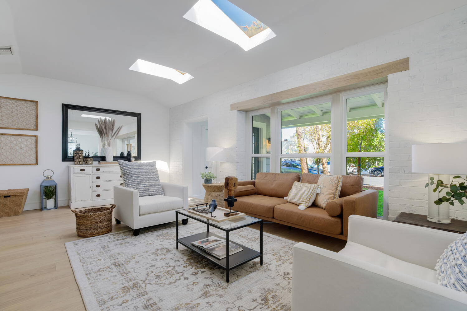 A living room with white furniture and a skylight.