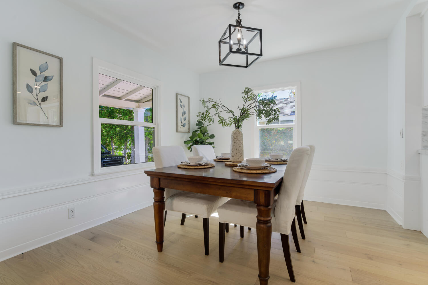 A dining room table with chairs and a vase of flowers.