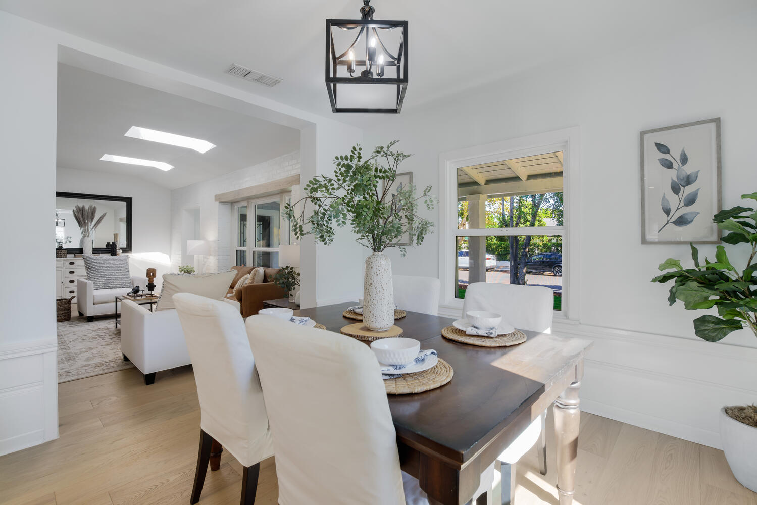 A dining room table with white chairs and a vase of flowers.