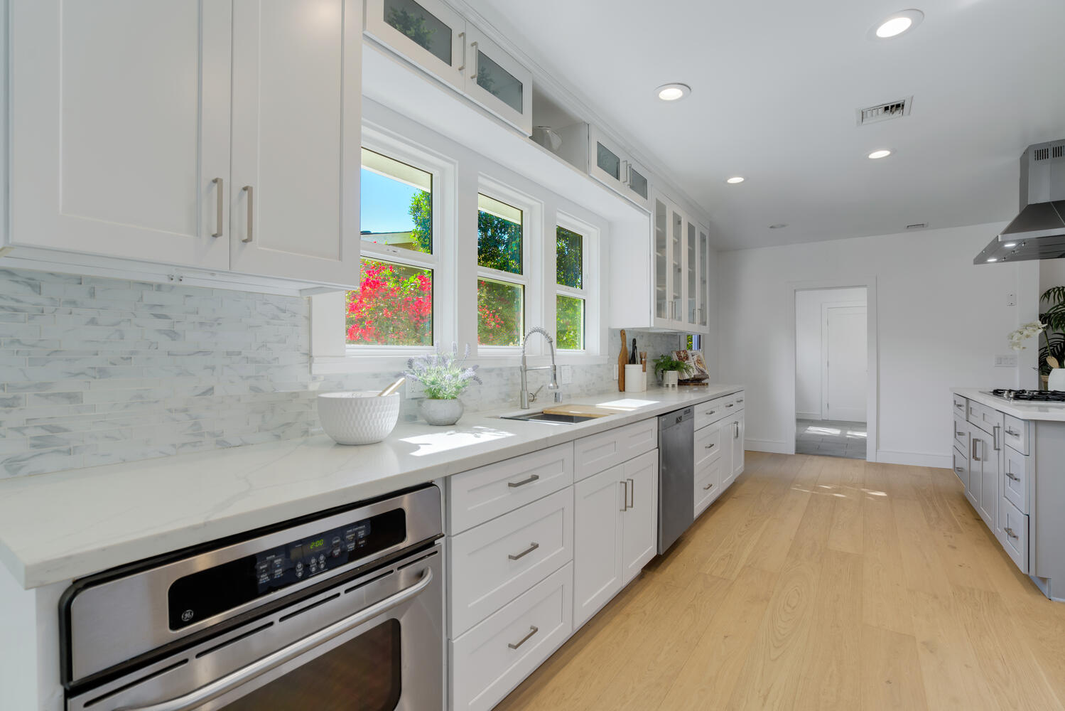 A kitchen with white cabinets and wooden floors.