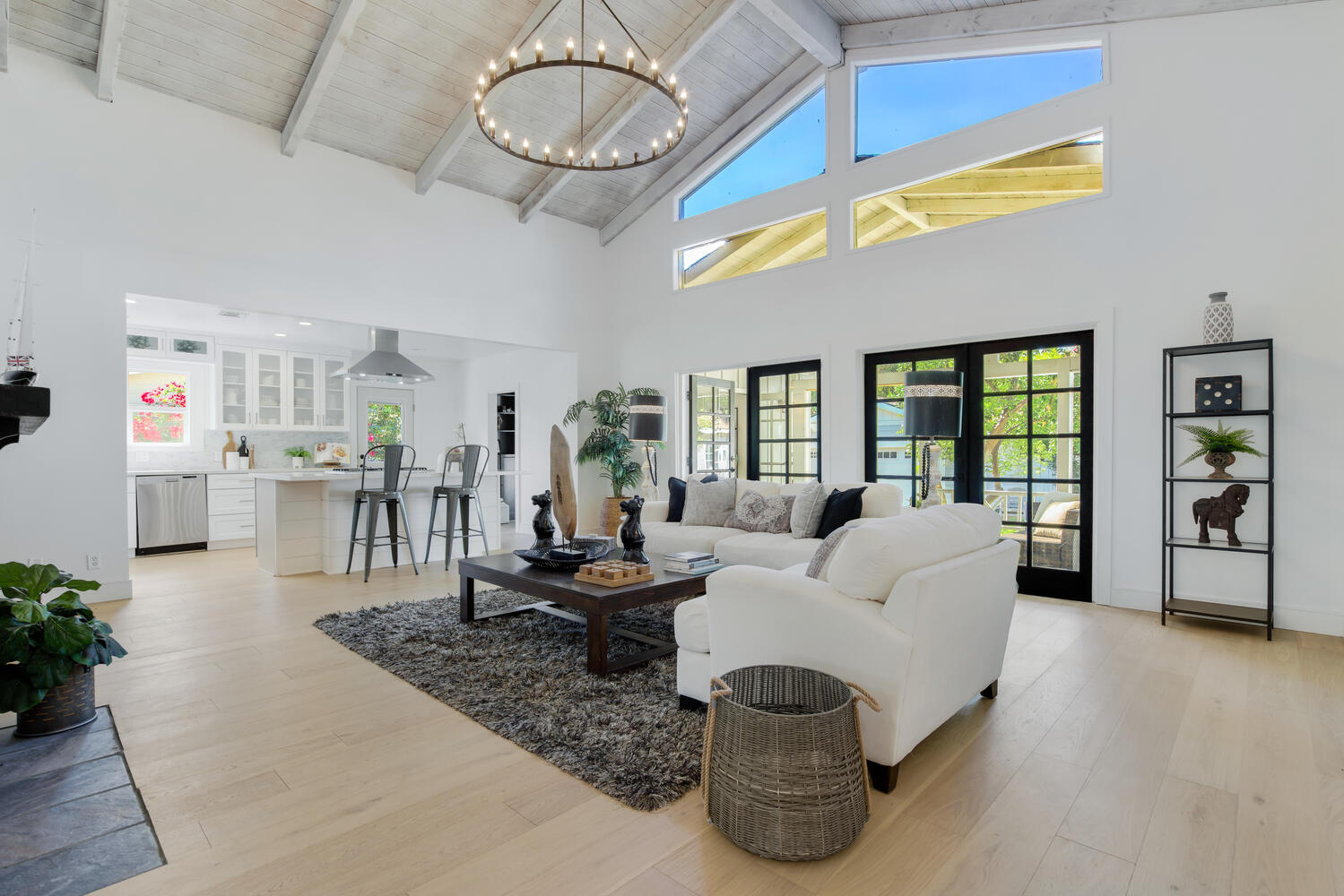 A living room with white furniture and large windows.