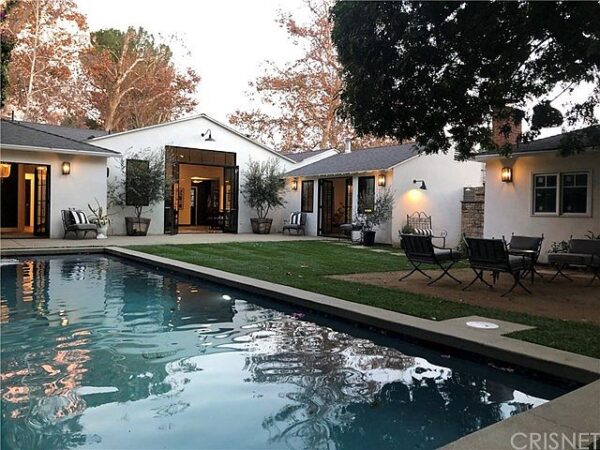 A pool with chairs and tables in the back yard.