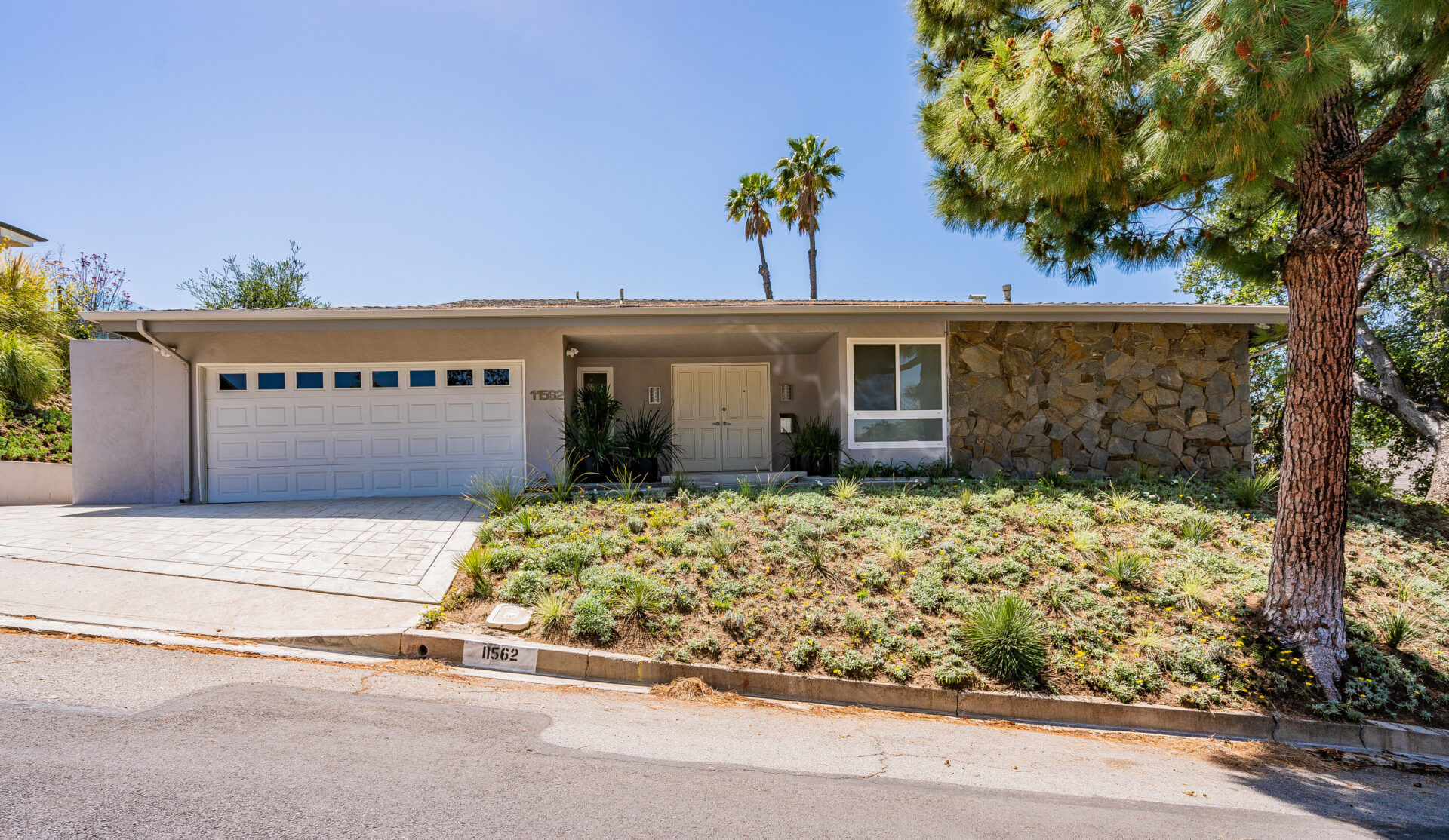 A house with a driveway and palm trees in the background.