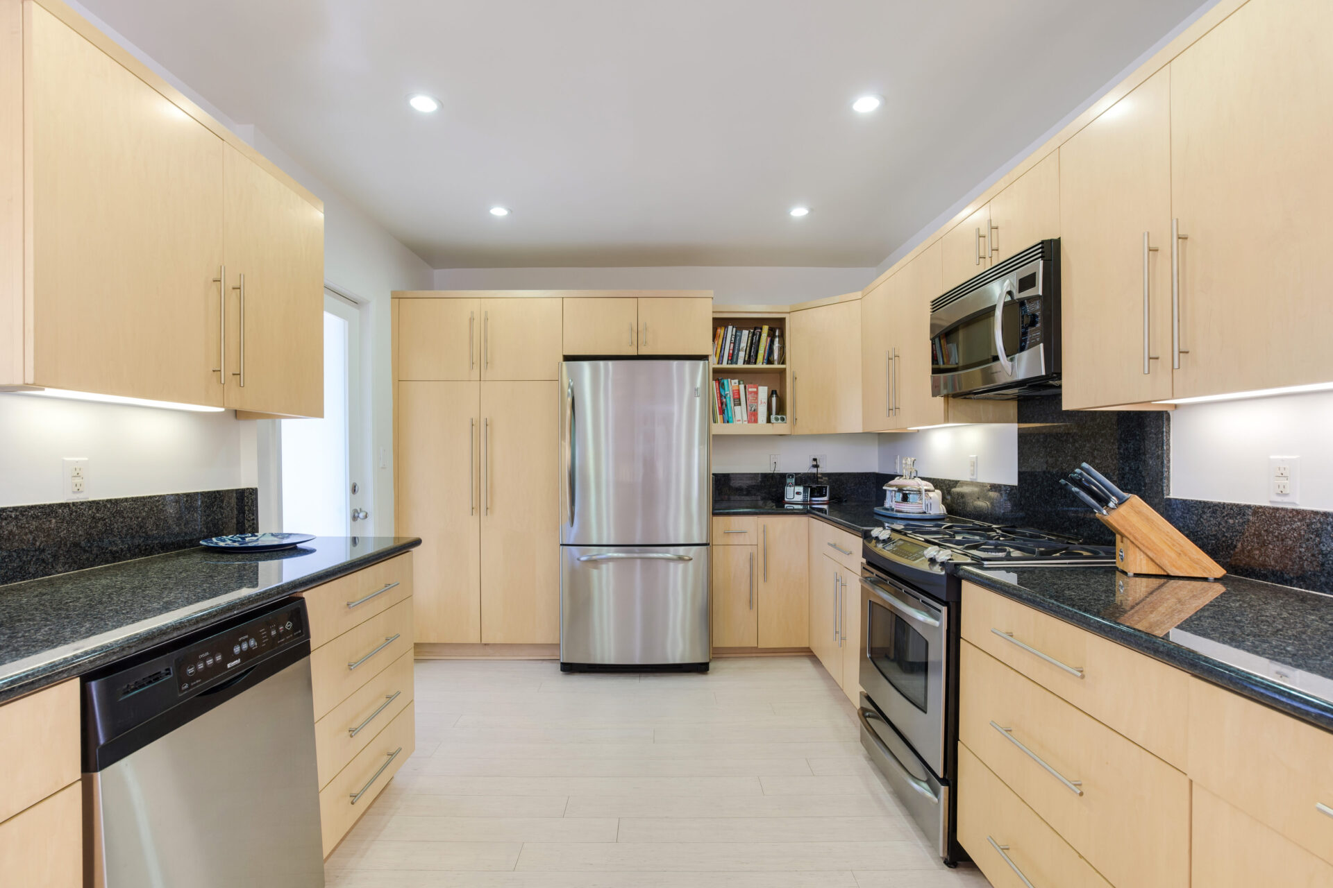 A kitchen with wooden cabinets and black counter tops.