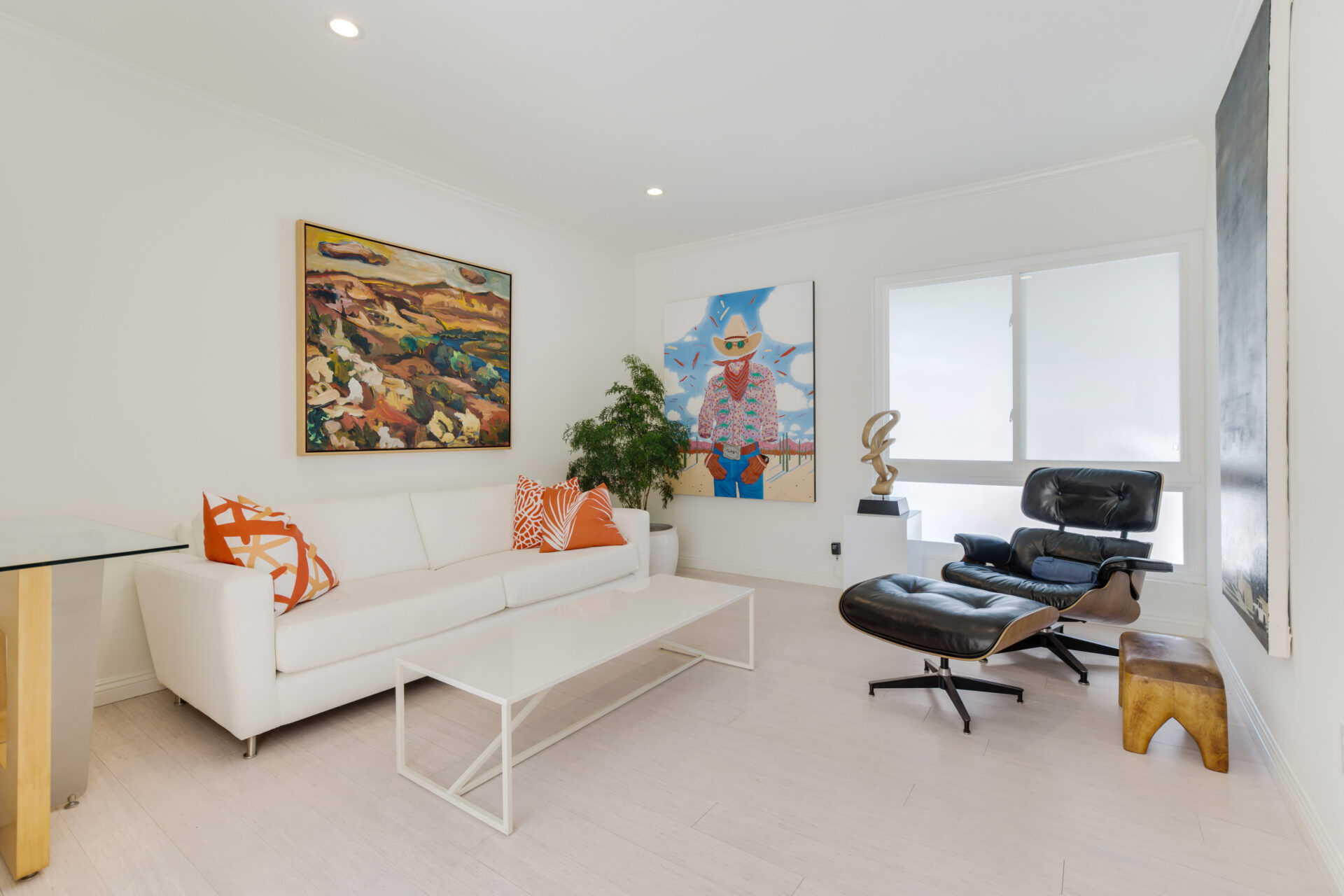 A living room with white furniture and a painting.