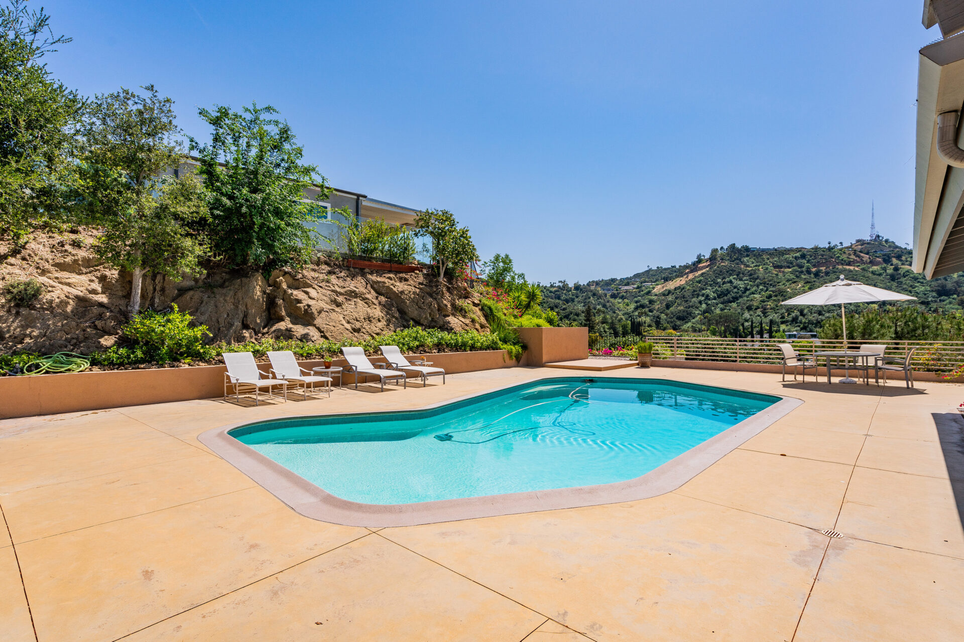 A pool with chairs and trees in the background.