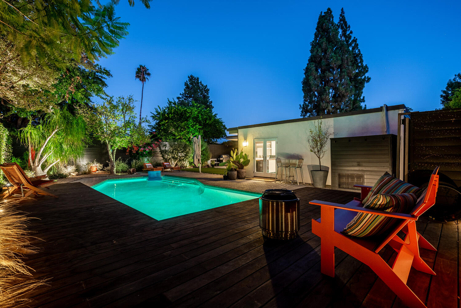 A pool with an illuminated swimming area in the back yard.