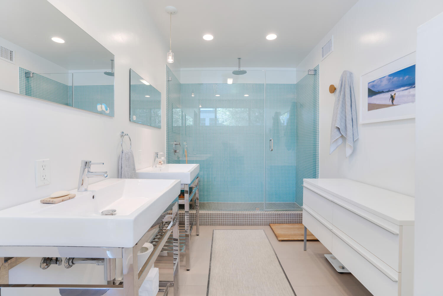 A bathroom with two sinks and a walk in shower.