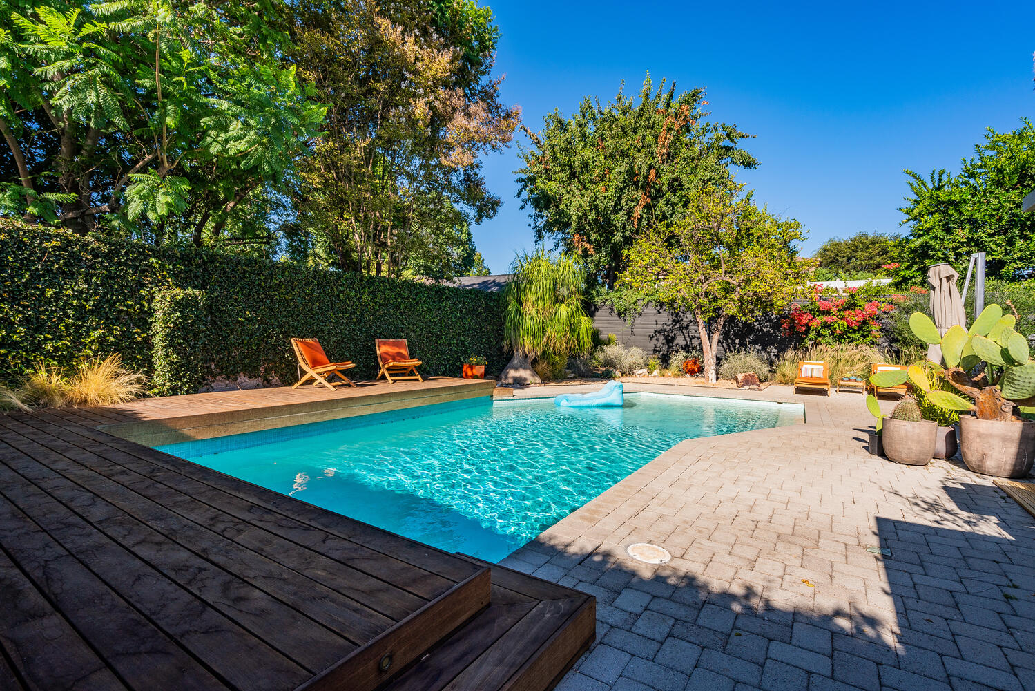 A pool with wooden steps and chairs around it.