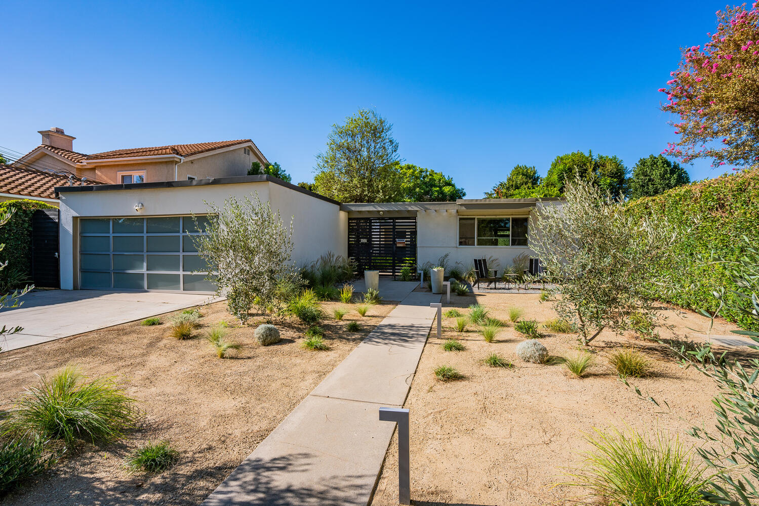 A house with a driveway and a lot of plants in it